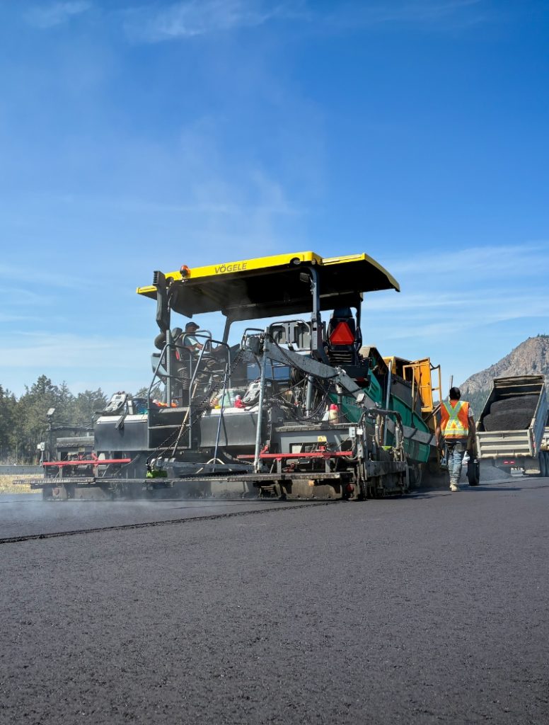 Vögele paver receiving asphalt from a dump truck on Highway 5 near Kamloops