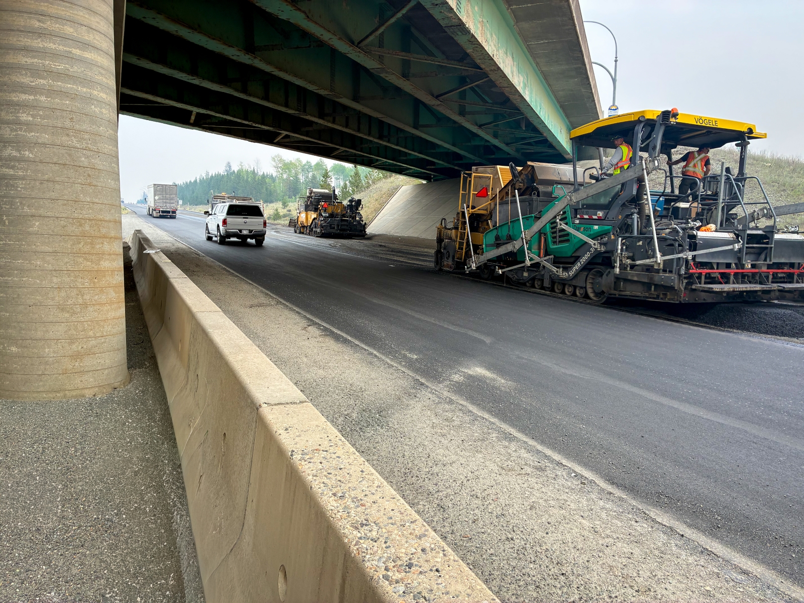 Dawson Construction paver placing asphalt under an overpass on Highway 5 near Kamloops